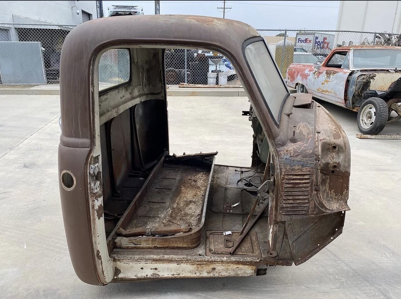 Vintage truck cab with heavy rust and brown paint before blasting