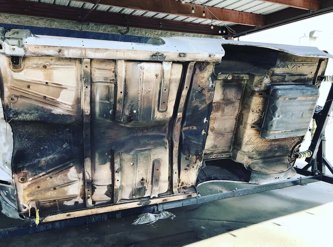 Underside of a truck cab covered in rust and old coatings