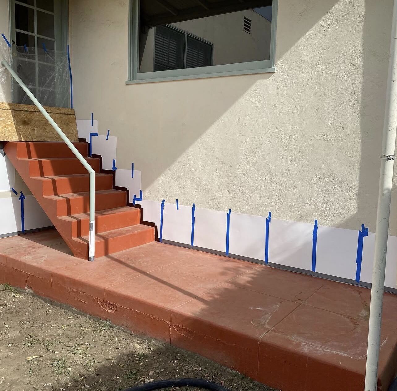 Concrete steps and porch painted red, masked off with tape and paper
