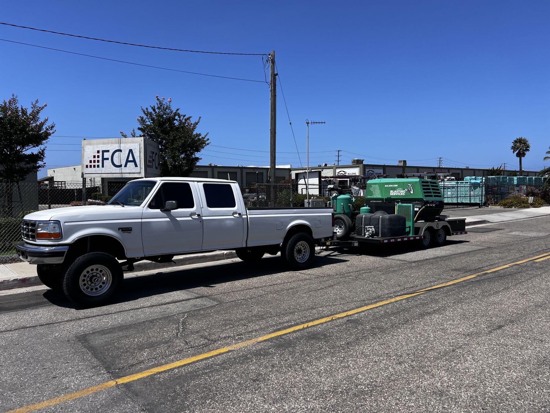 White pickup towing the green TCC Blasting Services mobile sandblasting trailer